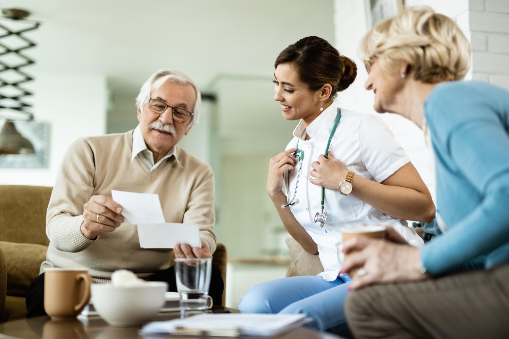 A happy mature couple showing photos to a female doctor visiting their home.